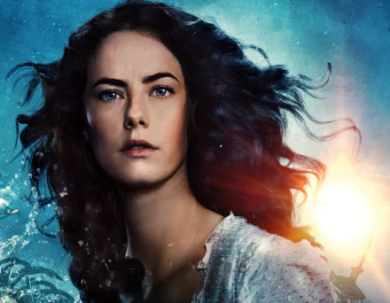 HD desktop wallpaper featuring Kaya Scodelario as Carina Smyth from Pirates of the Caribbean: Dead Men Tell No Tales, with her face illuminated against a vibrant, oceanic background.