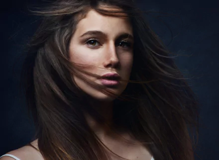 Close-up HD desktop wallpaper of a brunette woman with flowing hair and expressive brown eyes, capturing a serene and striking face.