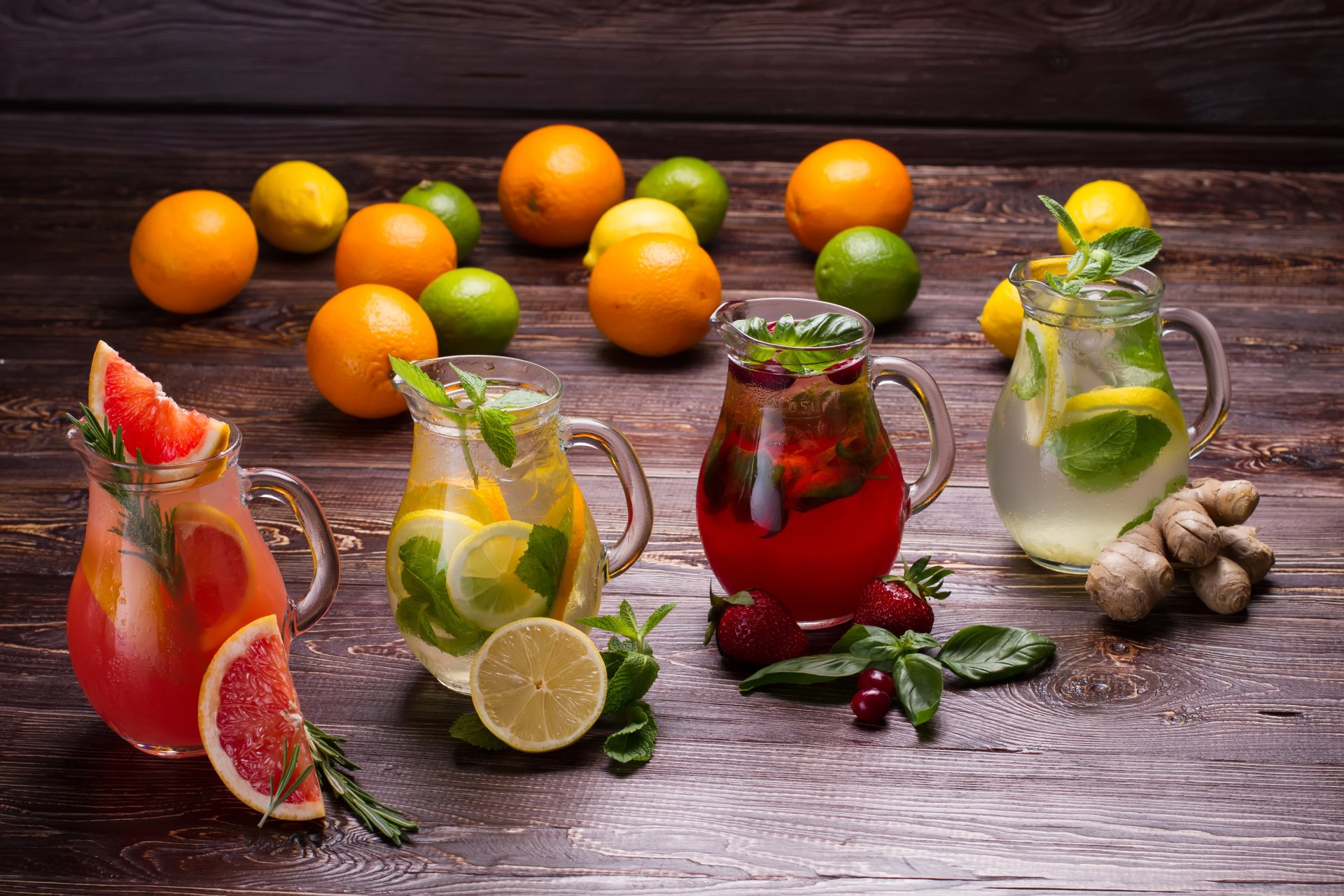 A vibrant 4K Ultra HD wallpaper featuring refreshing drinks garnished with grapefruit, strawberry, lemon, and fresh herbs on a rustic wooden table with assorted citrus fruits.