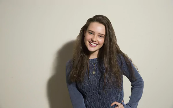 HD wallpaper of Australian actress Katherine Langford, a brunette with a bright smile, posing in a blue sweater.