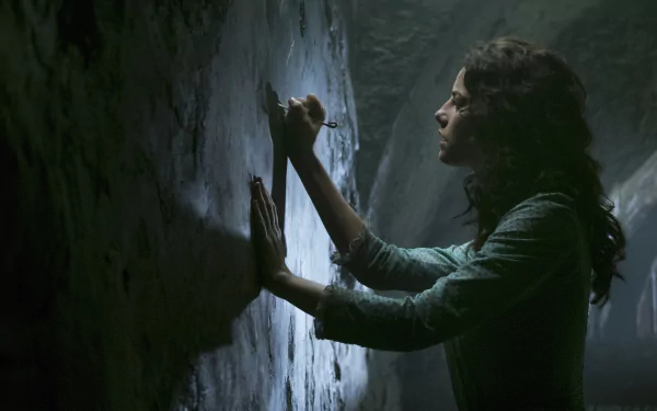 Carina Smyth, played by Kaya Scodelario in Pirates of the Caribbean: Dead Men Tell No Tales, examines an ancient wall in a 4K Ultra HD movie wallpaper.
