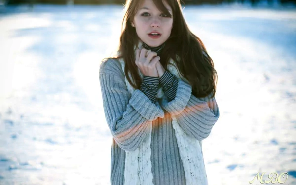 HD desktop wallpaper featuring actress and celebrity Melissa Benoist in a cozy sweater, standing outdoors in a snowy setting with soft natural lighting.