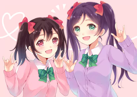 HD PC desktop wallpaper of Love Live! characters Nozomi Tojo and Nico Yazawa smiling and making cheerful hand signs, wearing school uniforms with green bows on a pink background.