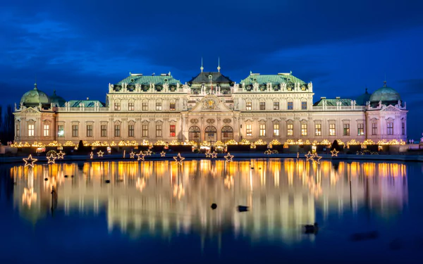 Night view of the illuminated Belvedere Palace in Vienna, Austria, reflected in calm water, captured in stunning 4K Ultra HD detail.