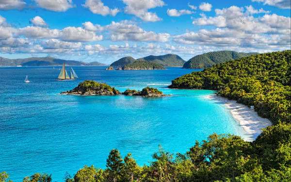 A stunning HD wallpaper showcasing a tropical bay with a sailboat, lush coastline, pristine beach, and a backdrop of islands under a vibrant sky with scattered clouds.