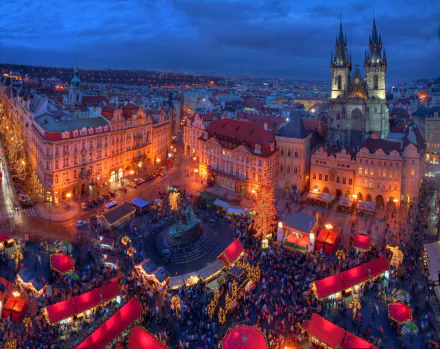 Nighttime cityscape of Prague's Christmas market in the Czech Republic, illuminated with festive lights and bustling crowds, captured in HD for a desktop wallpaper.