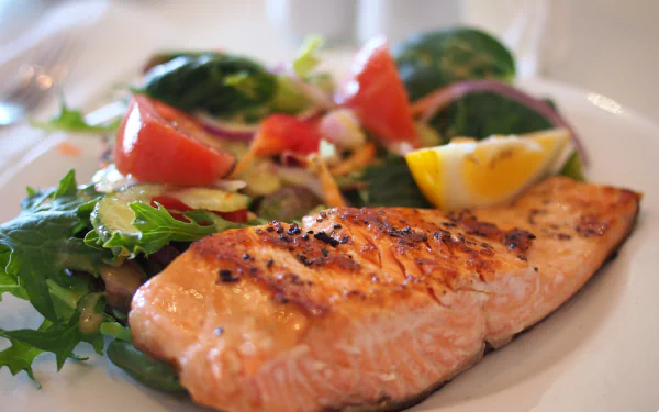 Close-up of a grilled salmon meal with fresh salad on a blurred background, showcased as an HD seafood desktop wallpaper.