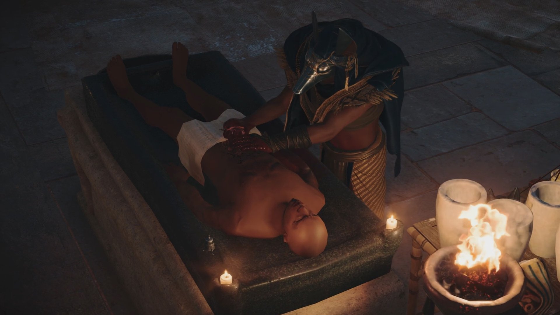 Assassin's Creed Origins (video game) 2K Quad HD PC desktop wallpaper: an Egyptian priest in a gold mask performs a ritual over a prone body on a stone slab, candles and a brazier glowing.