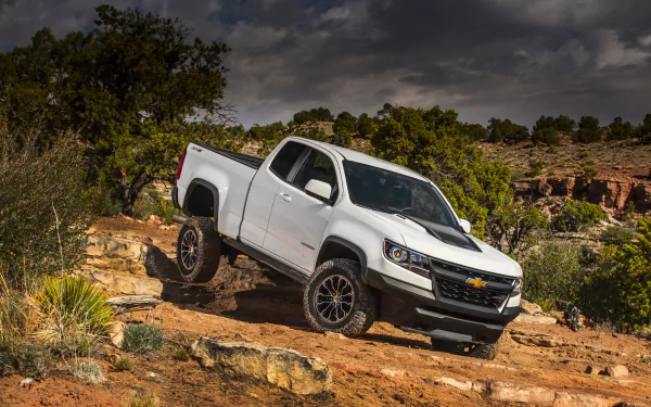 White Chevrolet Colorado ZR2 pickup on a rocky desert trail, off-road view of the Chevrolet vehicle — 2K Quad HD PC desktop wallpaper and background.