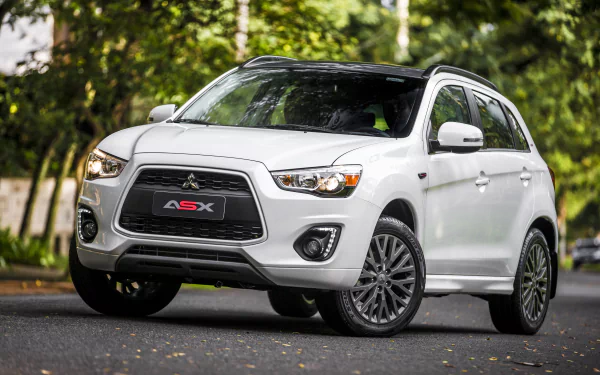 White Mitsubishi ASX SUV parked on a road with a green, leafy background, captured in sharp 4K Ultra HD quality as a desktop wallpaper and background.