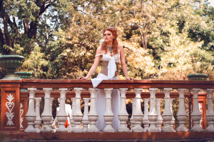 Cosplayer as Anna Henrietta from The Witcher 3: Wild Hunt in a white gown leaning on an ornate stone balustrade amid sunlit trees; 2K Quad HD PC desktop wallpaper/background.