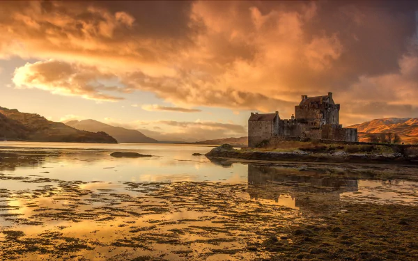 Eilean Donan Castle, a man-made stone castle on a Scottish lake, reflected in calm water under dramatic clouds — landscape HD PC desktop wallpaper background.