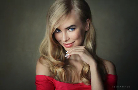 HD desktop wallpaper of a smiling blonde woman with striking blue eyes, softly curled hair, and a red off-shoulder top against a muted background.