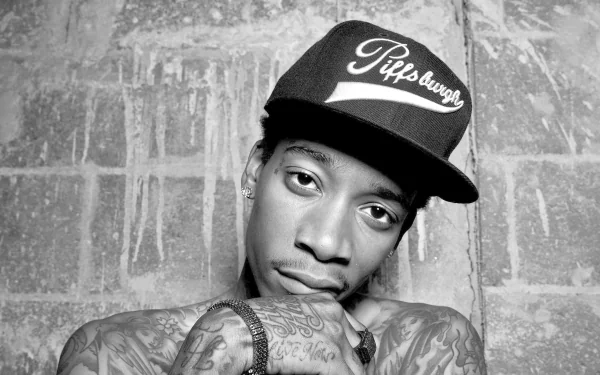 HD desktop wallpaper featuring a monochrome portrait of a man with tattoos wearing a Pittsburgh cap against a brick wall background.