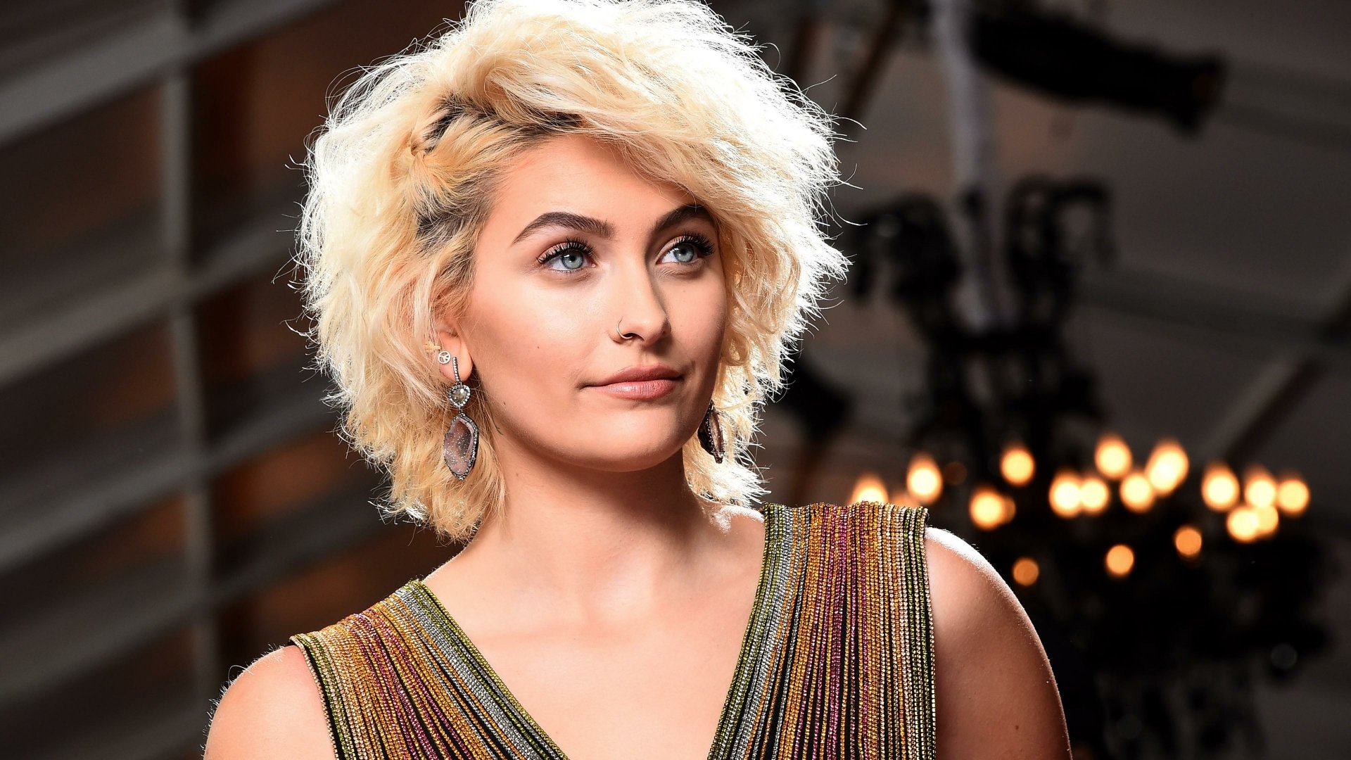 4K Ultra HD PC desktop wallpaper featuring celebrity Paris Jackson with short blond hair and a shimmering multicolored top against a softly lit background.