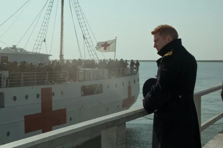 A HD desktop wallpaper featuring Kenneth Branagh from the movie Dunkirk, standing on a dock with a medical ship and its passengers in the background.
