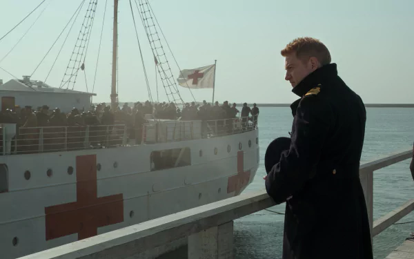 A HD desktop wallpaper featuring Kenneth Branagh from the movie Dunkirk, standing on a dock with a medical ship and its passengers in the background.