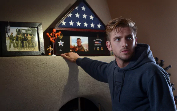 HD desktop wallpaper featuring Dan Stevens with a contemplative expression, next to a shelf with military memorabilia.