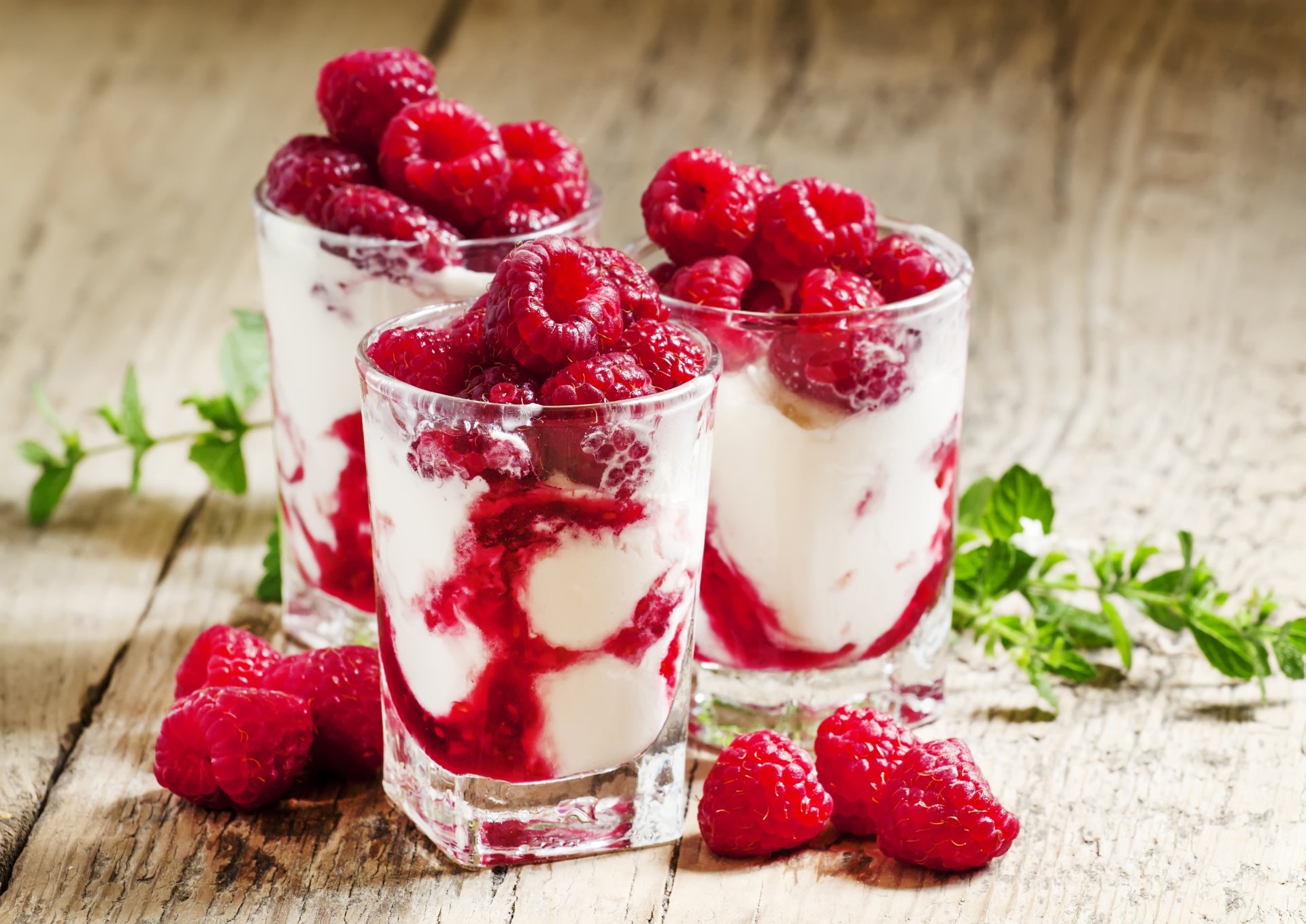 Close-up of fresh raspberries layered with creamy yogurt in glasses, captured as a vibrant 4K Ultra HD dessert wallpaper and background.