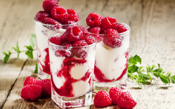 Close-up of fresh raspberries layered with creamy yogurt in glasses, captured as a vibrant 4K Ultra HD dessert wallpaper and background.
