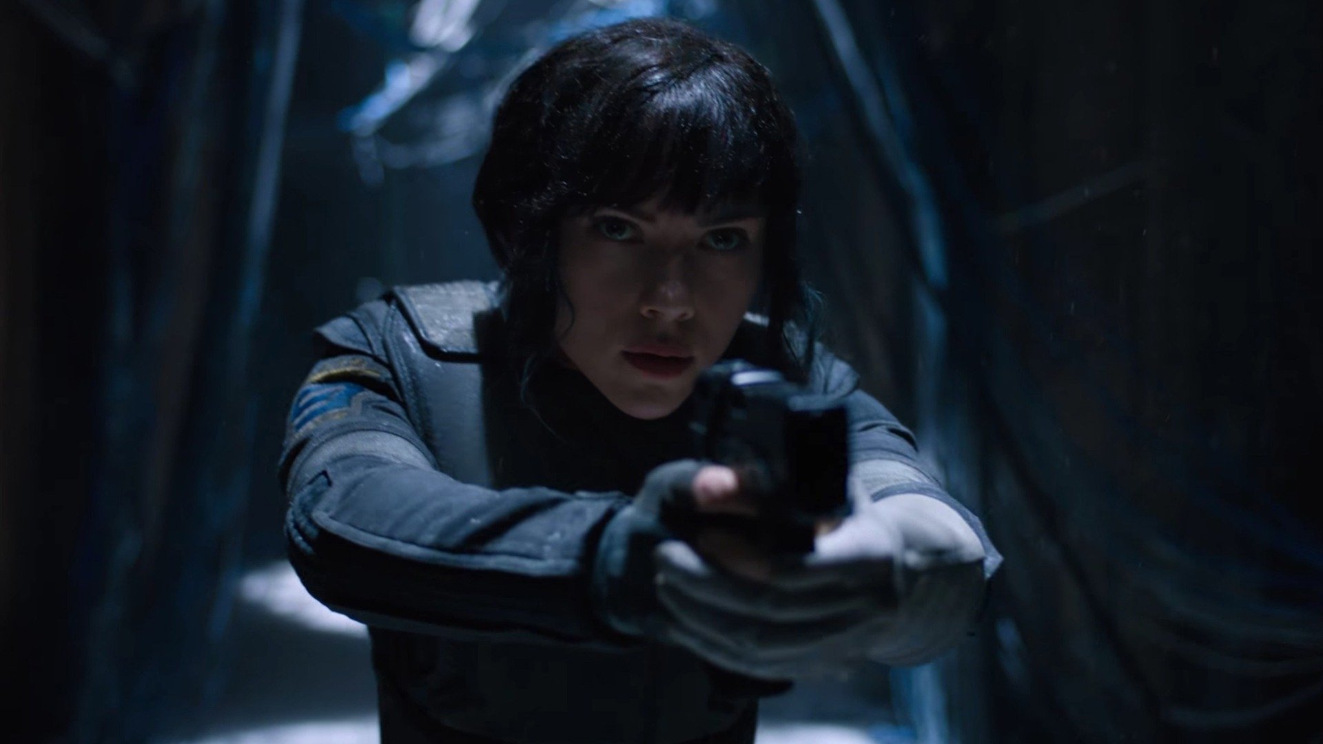 HD desktop wallpaper featuring Scarlett Johansson in a dark, intense scene from the 2017 movie Ghost in the Shell, aiming a handgun forward.