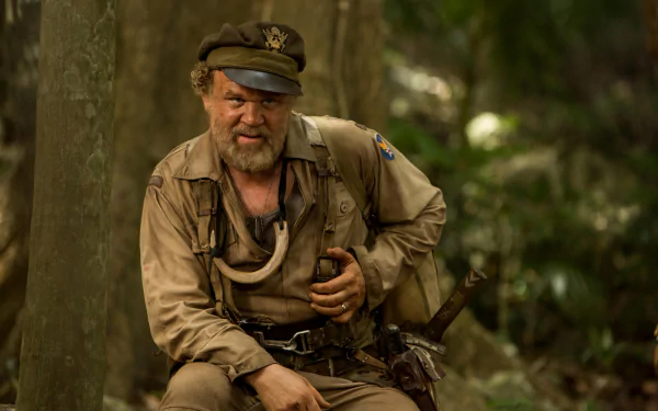 Bearded soldier crouches in a lush jungle holding a radio and knife - 5K Ultra HD PC desktop wallpaper background from the movie Kong: Skull Island