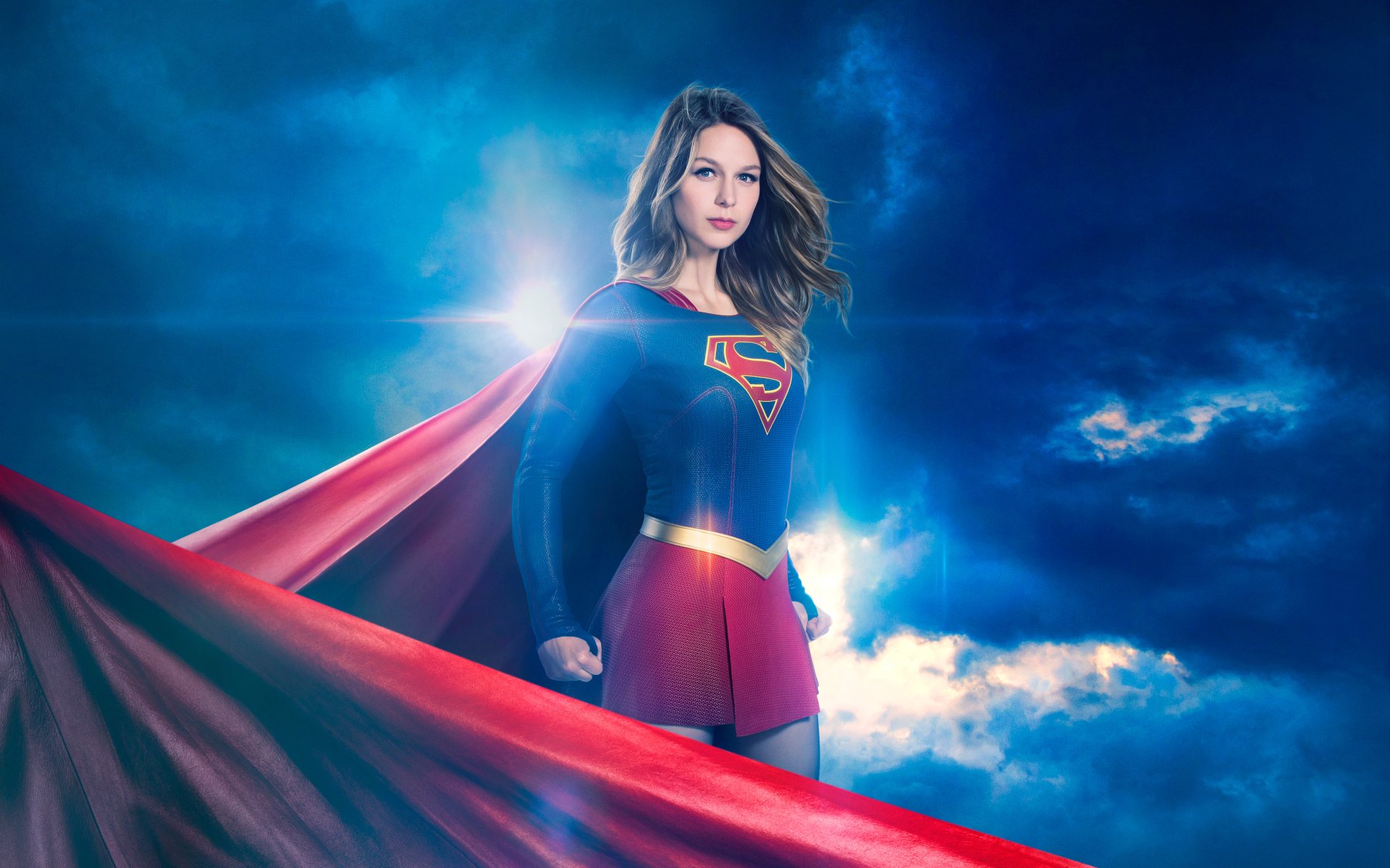 Melissa Benoist as Supergirl in a dramatic pose against a stormy sky, featured in a 4K Ultra HD TV show desktop wallpaper and background.