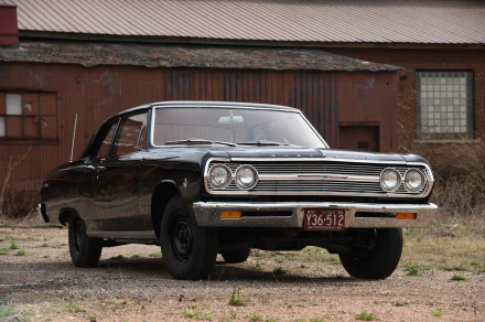 HD PC desktop wallpaper showing a black Chevrolet Chevelle muscle car parked before a weathered barn, a classic Chevrolet vehicle with chrome grille and vintage styling.