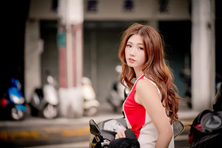A redhead Asian woman model with softly curled hair poses outdoors, captured with a shallow depth of field in vibrant 4K Ultra HD detail.