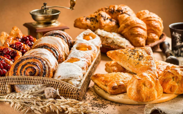 HD desktop wallpaper featuring an assortment of viennoiserie including croissants and pastries, styled as a delicious breakfast spread.
