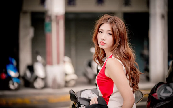 A redhead Asian woman model with softly curled hair poses outdoors, captured with a shallow depth of field in vibrant 4K Ultra HD detail.