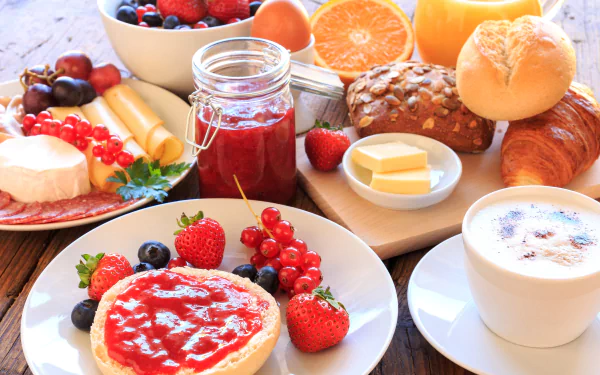 A vibrant 4K Ultra HD breakfast spread featuring cheese, viennoiserie, fresh berries, fruit, jam, and a cup of coffee on a wooden table.