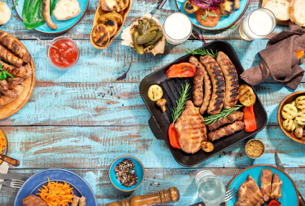 5K Ultra HD PC desktop wallpaper and background: a food still life of grilled sausages and assorted meats with sides, sauces and bread on a rustic blue table.