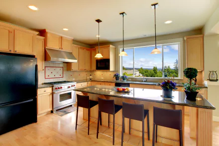 A bright kitchen featuring modern wood cabinetry, a black refrigerator, and a spacious island with seating, set against a scenic window view, captured in 4K Ultra HD.