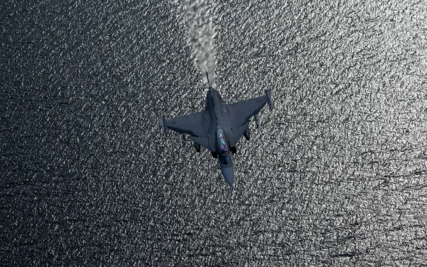 A Saab JAS 39 Gripen jet fighter warplane flies over textured water, captured in a high-definition military aircraft desktop wallpaper.
