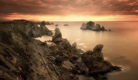 Sepia-toned HD desktop wallpaper of a rocky coastline under cloudy skies with the ocean stretching to the horizon, capturing nature’s serene beauty.