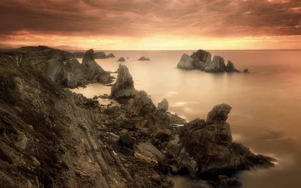 Sepia-toned HD desktop wallpaper of a rocky coastline under cloudy skies with the ocean stretching to the horizon, capturing nature’s serene beauty.