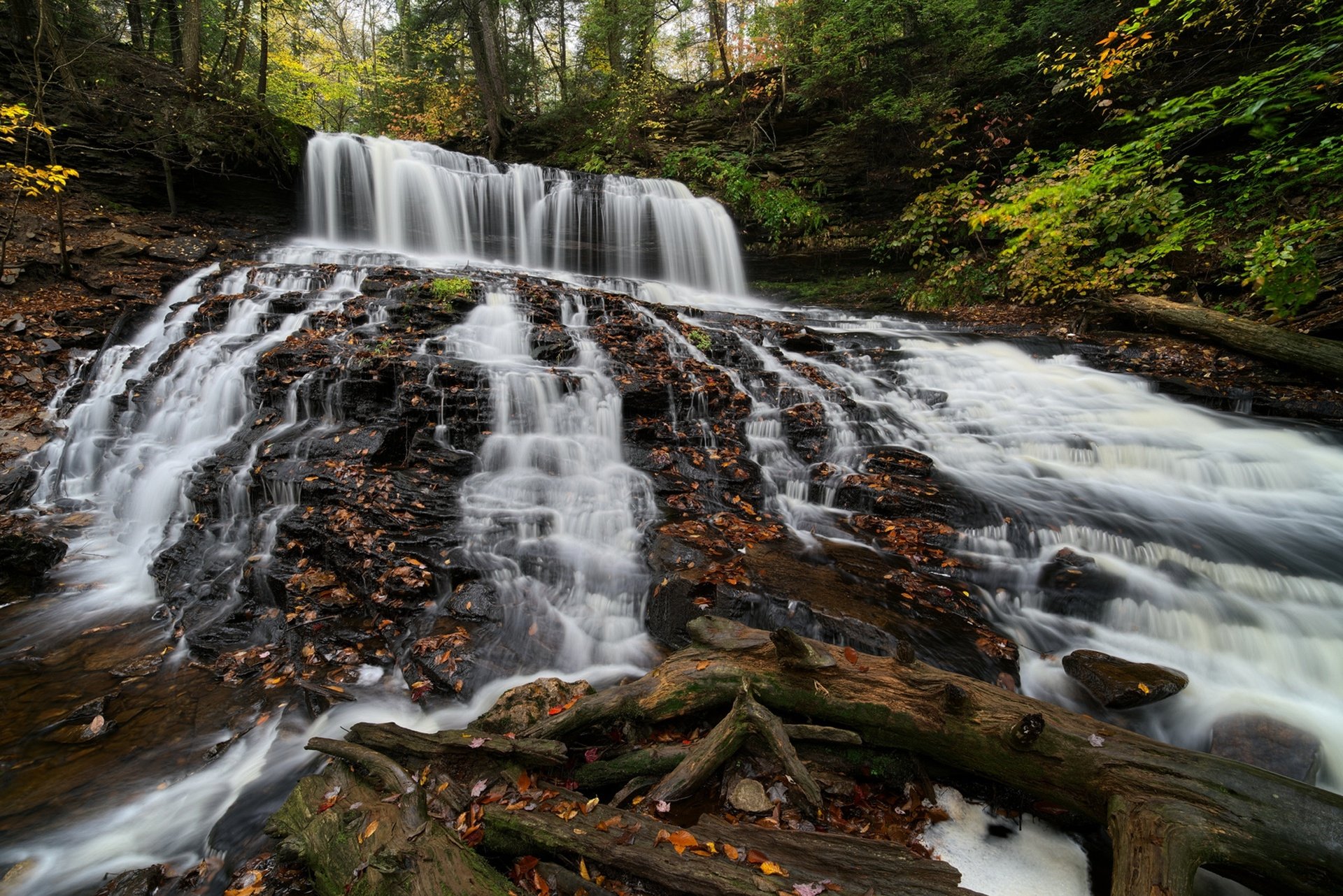 HD PC desktop wallpaper and background: foamy stream cascading over rocky ledges into a multi-tiered waterfall, surrounded by mossy rocks and lush green forest.