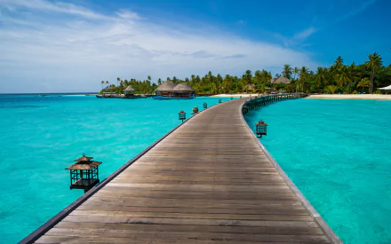 A 4K Ultra HD desktop wallpaper showing a wooden pier extending over turquoise ocean waters toward a tropical island with palm trees in the Maldives.