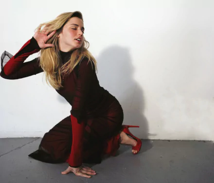 HD PC desktop wallpaper: blonde female celebrity kneeling in a burgundy dress and red heels, posing against a plain white wall.