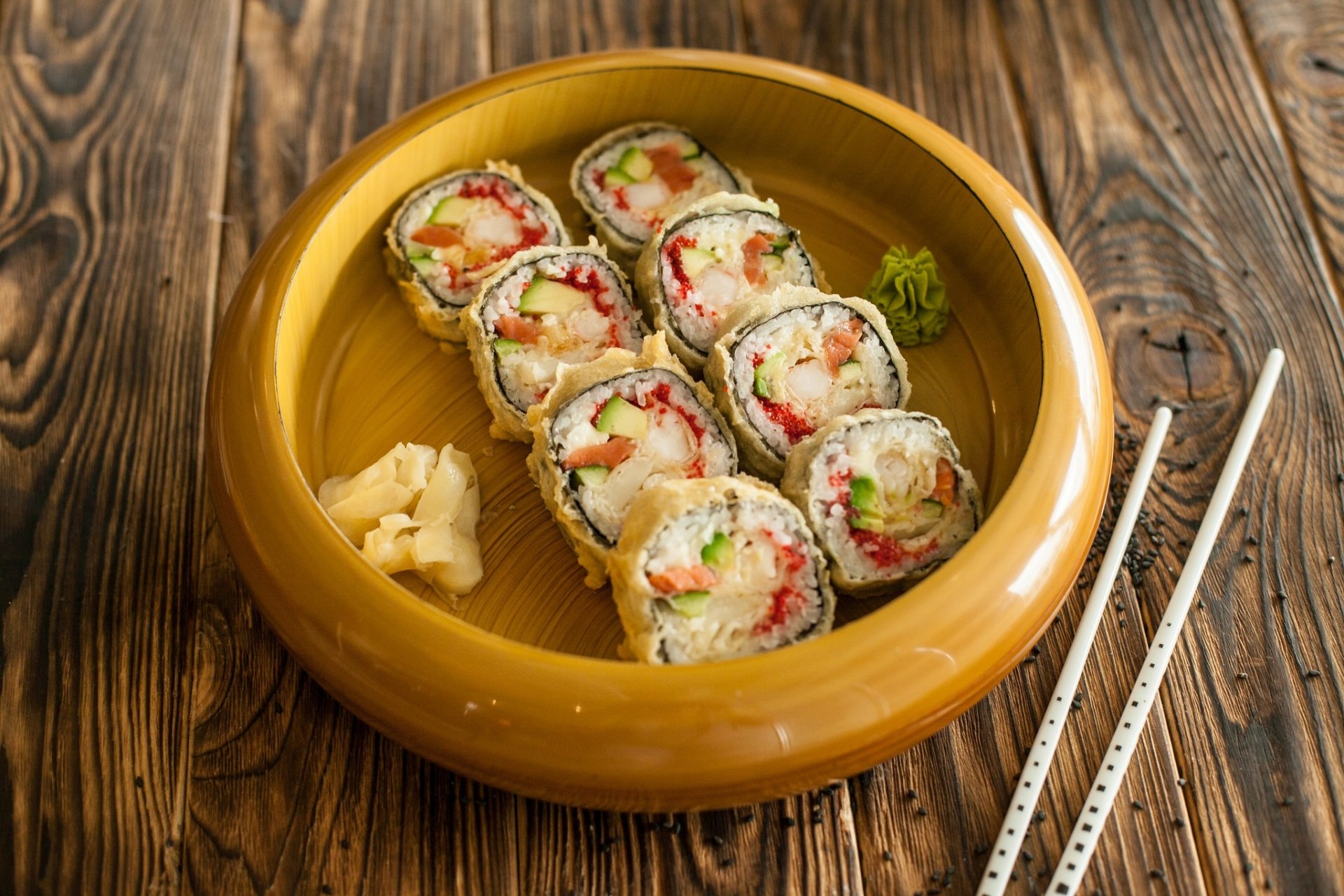 HD desktop wallpaper featuring sushi rolls with seafood, rice, and fish served in a wooden bowl alongside chopsticks on a rustic wooden table.