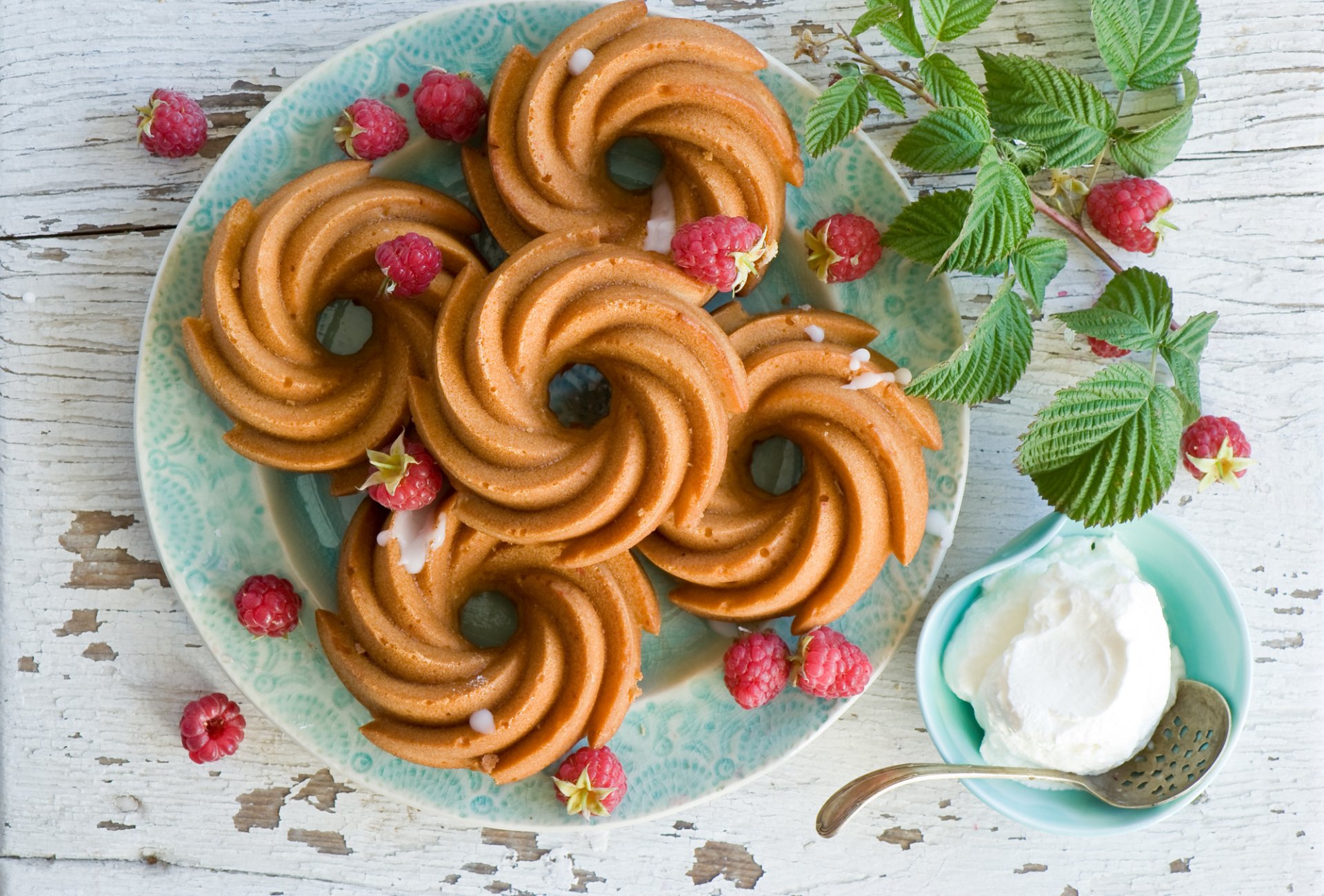 HD desktop wallpaper featuring a still life of spiral cookies and fresh raspberries on a blue plate with a small bowl of cream on a rustic wooden surface.