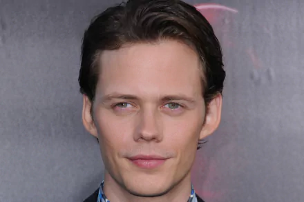 Close-up portrait of a smiling man with dark hair and light skin against a neutral backdrop — 2K Quad HD PC desktop wallpaper.