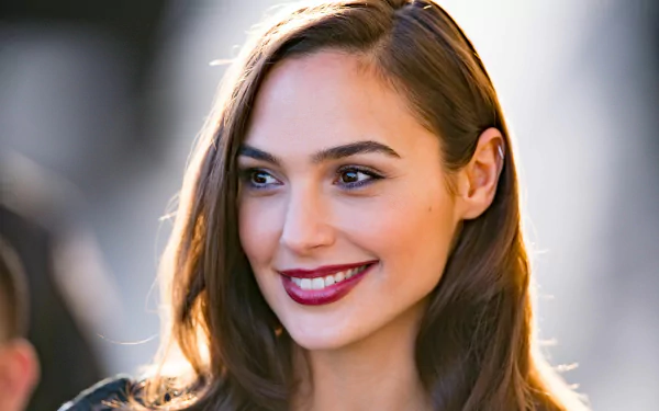 A high-definition desktop wallpaper featuring a smiling brunette with brown eyes and lipstick, tagged as an Israeli model and actress.