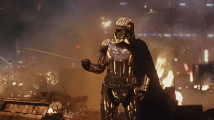 Captain Phasma, portrayed by Gwendoline Christie, stands in reflective armor amid destruction in a dramatic scene from Star Wars: The Last Jedi.