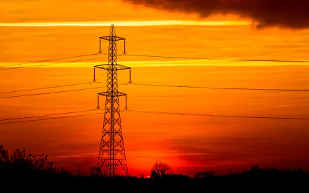 HD desktop wallpaper of a power line tower silhouetted against a vibrant orange and yellow sunset sky.