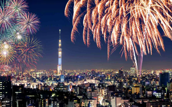 Night cityscape of Tokyo with the illuminated Tokyo Skytree and colorful fireworks lighting up the sky above the urban horizon in Japan.