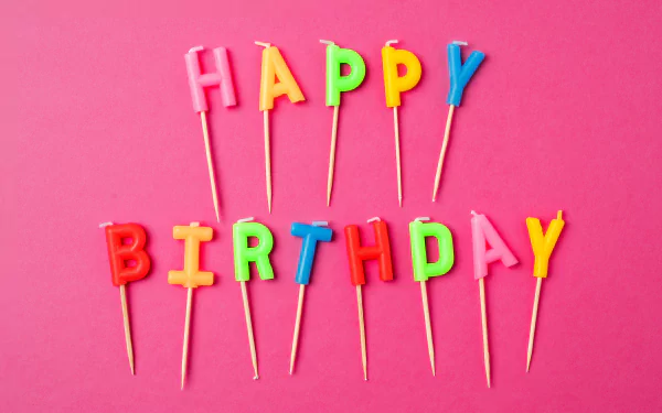 Colorful Happy Birthday candles arranged on a pink background, captured in vibrant 4K Ultra HD for a bright holiday-themed PC desktop wallpaper.