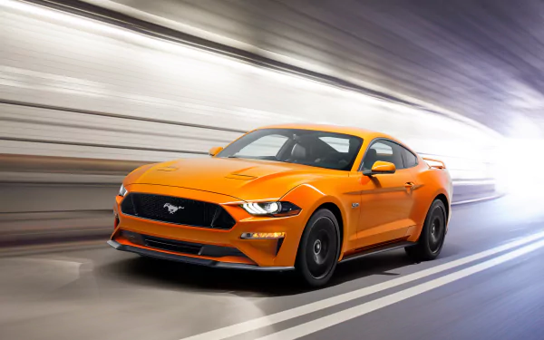 HD desktop wallpaper featuring an orange Ford Mustang GT supercar speeding through a blurred tunnel.