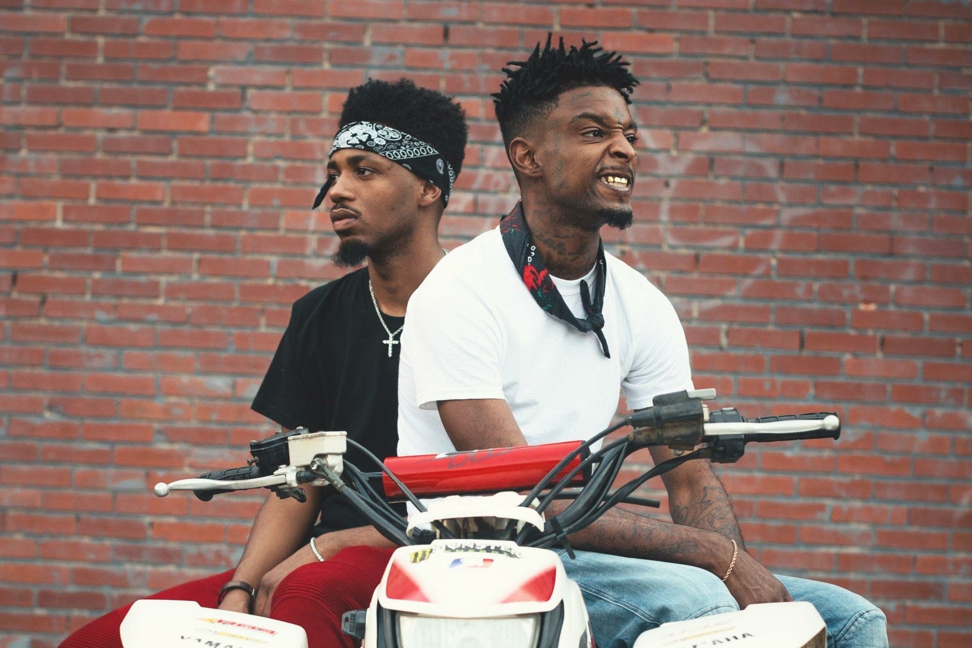HD desktop wallpaper featuring two individuals on a motorbike against a brick wall background, tagged with 21 Savage.